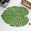 Goudgroene Monstera blad placemat met hol mesh ontwerp op wit marmeren tafel - Groen