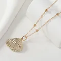 Golden shell pendant necklace with bead chain on white stone, minimalist coastal style jewelry - KC Gold