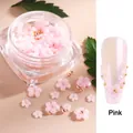 Detail of pink resin flowers and golden beads on purple nails with square bottle - Pink