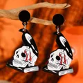 Gothic raven skull earrings on a dry branch with a moody orange background for Halloween - Raven on Skull Book