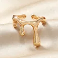 Détail d'une bague dorée forme goutte fluide sur fond de soie plissée beige - Style Goutte de Liquide (WR1028)