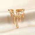 Détail macro d'une bague dorée au design liquide fondu sur fond de soie champagne - Structure Fluide Créative (WR1029)