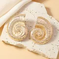 Dettaglio orecchini a spirale a forma di nautilus dorati su superficie in pietra ruvida - Stile Conchiglia a Spirale Oro (WEH4926)