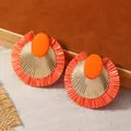 Dettaglio orecchini con nappe in rafia arancione con disco dorato e resina ovale - Stile Nappina in Rafia Arancione (WEH4880)