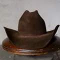 Vintage dark brown cowboy felt hat with wide brim on rustic wooden tray background - Brown