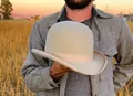 Beige pure wool bowler hat with matching grosgrain ribbon held by a man outdoors - Beige