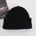 Close-up of thick ribbed knit texture on a black winter beanie with a stylish background - Adult / Black
