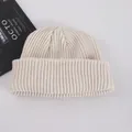 Cream white ribbed knit beanie with folded cuff shown from a top-down lifestyle view - Adult / Beige