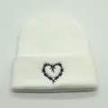 Dettaglio di un berretto in maglia bianca con ricamo a cuore in filo spinato nero - M / Bianco