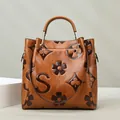 Brown leather tote bag featuring embossed floral patterns and circular top handles - Yellow Brown