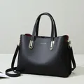 Bolso tote minimalista negro con textura granulada, detalles dorados y forro interior rojo - Negro