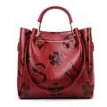 Red bucket bag with embossed monogram patterns and gold hardware detail - Burgundy