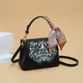 Elegant black crossbody bag featuring floral embroidery and a decorative handle scarf - Black