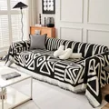 Close-up of black and white geometric chenille sofa cover with decorative tassel edges - 180x130 / Black