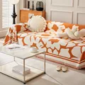 Gros plan du jeté de canapé en tricot avec motif floral orange et franges décoratives - Orange