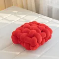 Coussin noué rouge fait main avec texture tressée sur un matelas blanc doux - Rouge Orangé