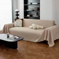 Funda de sofá beige con tejido tipo gofre y flecos decorativos en salón moderno - Caqui
