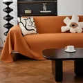 Funda de sofá de punto gofre naranja quemado con flecos sobre un sofá blanco - 180x90cm / Caramelo