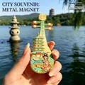 Hand holding a Hangzhou West Lake souvenir metal fridge magnet shaped like a Pipa - BXT0345 Pipa Shape West Lake Scenery Style