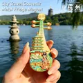 Hand holding a Hangzhou West Lake souvenir metal fridge magnet shaped like a Pipa - BXT0345 Pipa Shape West Lake Scenery Style