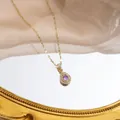 Macro detail of golden teardrop pendant with purple center stone and white crystals - X008