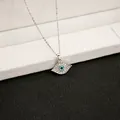 Macro shot of a silver evil eye pendant with blue crystals on a thin necklace chain - X142/full Diamond Eyes