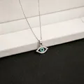 Detailed view of silver evil eye pendant with clear crystals and blue center on fine chain - X143/flat Glasses