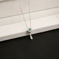 Close-up of a silver-toned necklace featuring an evil eye disc and teardrop pendant - Silver Round Eye Waterdrop Pendant Necklace