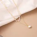 Detail of layered gold snake chain and delicate white pearl necklace on silk fabric - X756-2