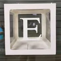 Détail d'une boîte à ballons blanche avec fenêtre transparente et lettre E décorative - Lettre E / Blanc