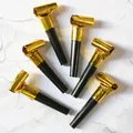Close-up of golden metallic party blowouts with black plastic mouthpieces on marble - New Year Gold