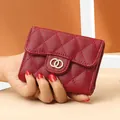 Short burgundy quilted leather wallet with gold interlocking buckle held by a hand - Burgundy