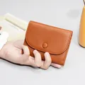 Mini portamonete in pelle marrone con chiusura a scatto tenuto in mano - Giallo ocra