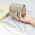 Beige Mini-Umhängetasche aus genarbtem Leder mit goldener Kette in der Hand - Hellgrau
