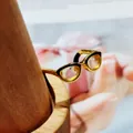 Creative gold glasses-shaped ring with black enamel accents on a wooden stand - Gold Eyeglasses Style (3)