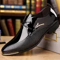 Close-up of black patent leather dress shoe with honeycomb texture and gold metal accents - Black 1879
