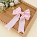 Detailed view of pink satin bow hairclip with lace edges and ribbons on wooden tray - Light Pink