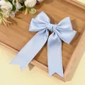 Detail of light blue satin hair bow clip with elegant ruffled lace edges and long ribbons - Light Blue