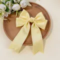 Detailed view of the yellow satin bow hair clip with elegant scalloped lace edges - Yellow