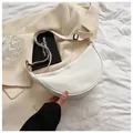 Minimalist white crescent shoulder bag shown on beige blazer in a lifestyle setting - White