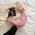 Close-up of a pink nylon crescent bag with adjustable strap on a neutral background - Pink