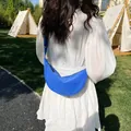 Blue nylon crescent crossbody bag for women shown in an outdoor lifestyle camping setting - Blue
