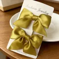 Pair of olive green satin bow hair clips for girls displayed on a white card - Satin Bow / 2 Pcs/Set / Turmeric
