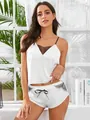 Detailed view of white satin camisole set with black lace trim and bow-tie shorts - One Size / White
