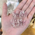 Rosa Schmetterlingsnägel zum Aufkleben mit 3D-Flügeln und Perlen auf langen Sargnägeln - Box-Stil