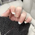Close-up of French tip press-on nails with glitter accents and a small rhinestone - Phototherapy Glue Style / BY1284 Creamy White French