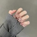 Dettaglio ravvicinato di unghie finte pink cat-eye con cuori 3D e strass scintillanti - Base Arancio Strass Rosa (BY1526) / Stile Colla per Fototerapia