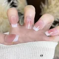Detail of French nude pink gradient press-on nails with white bows and glitter finish - Boxed Full Set