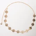 Dettaglio della catena da vita in metallo dorato con ciondoli a moneta vintage e chiusura a moschettone - Stile Moneta a Strato Singolo / Oro