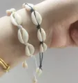 Detalle de pulseras de conchas tejidas a mano en blanco y negro para estilo playero - Blanco